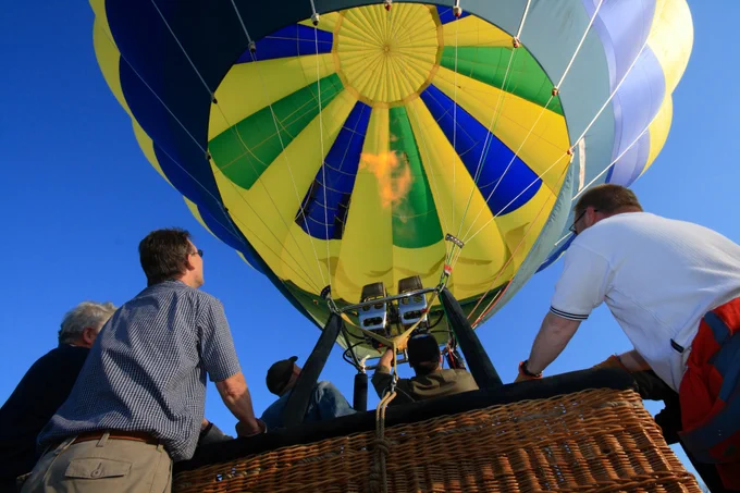Several people looking up into a hot air balloon. 