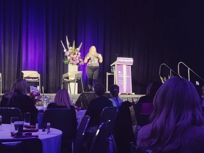 Cairo Malet speaks on the stage of Women In Technology Western Australia conference about the human conditions that makes us a cyber security risk.