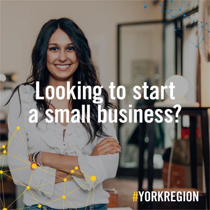 A young woman in standing in her small business with her arms crossed. 