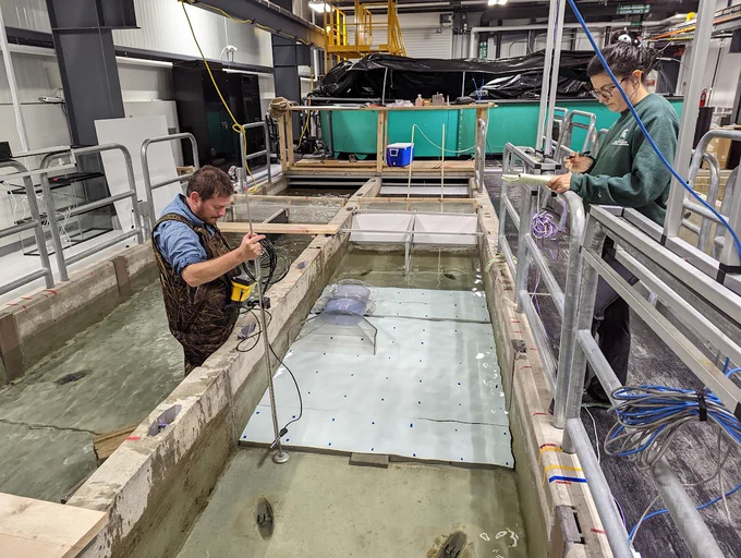Two people taking measurements in a large tank of water
