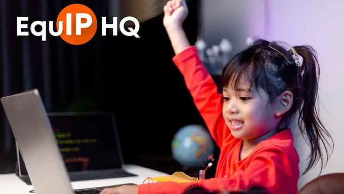 A photo of a young girl using a laptop at a table with another laptop and robotic car parts nearby. The girl is smiling and has her right fist up in the air in celebration. There is an EquIP HQ logo in the top left corner.