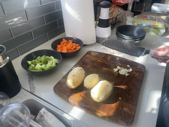 Raw ingredients of celery, carrots, potatoes and garlic being prepped for stew