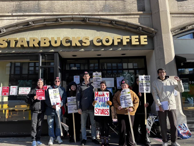 A group of baristas and community supporters stand outside the Starbucks shop at Coolidge Corner holding pro-union signs and leaflets.