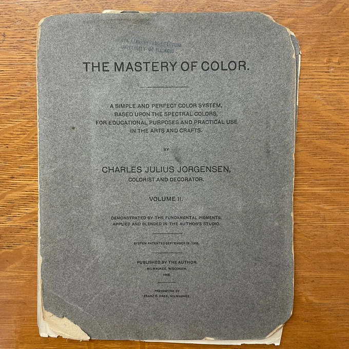 Image of a square board that reads, “THE MASTERY OF COLOR.
A SIMPLE AND PERFECT COLOR SYSTEM, BASED UPON THE SPECTRAL COLORS, FOR EDUCATIONAL PURPOSES AND PRACTICAL USE IN THE ARTS AND CRAFTS.
BY
CHARLES JULIUS JORGENSEN, COLORIST AND DECORATOR
VOLUME I
DEMONSTRATED BY THE FUNDAMENTAL PIGMENTS APPLIED AND BLENDED IN THE AUTHOR'S STUDIO,
SYSTEM PATENTÉD SEPTEMBER 16. 1902.
PUBLISHED BY THE AUTHOR
MILWAUKEE WISCONSIN
1906
PRESSWORK BY
FRANZ D. HAKE, MILWAUKEE,” 