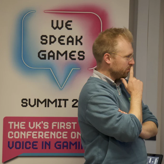 Speaker Thomas Keane standing infront of the We Speak Games summit banner