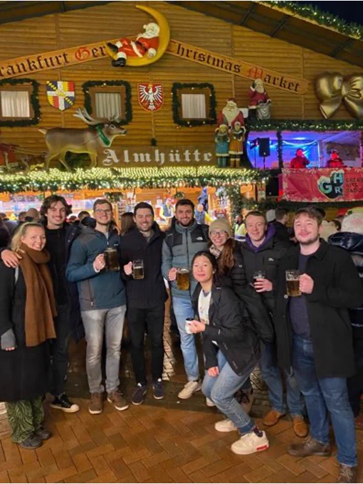 The image shows a group picture with 9 people in front of one of the Birmingham's Frankfurt Christmas Market stalls.