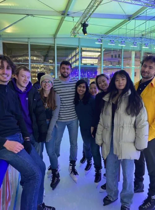 The image shows a group of 9 EngD students posing as a group at the Ice Rink.
