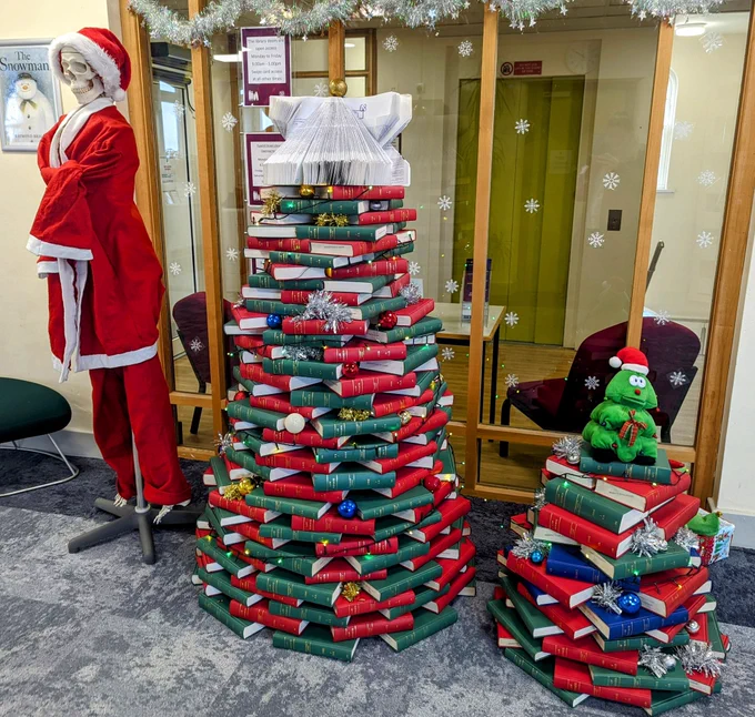 A festive display. A skeleton dressed as father Christmas.
Two Christmas trees made from piled up green and red law journals. 