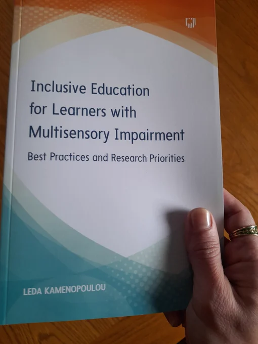 My hand holding the book 'Inclusive Education for Learners with Multisensory Impairment: Best Practices and Research Priorities'. The front cover side is visible. 