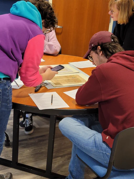 Students view manuscript leaves with their professor during a visit to Special Collections.