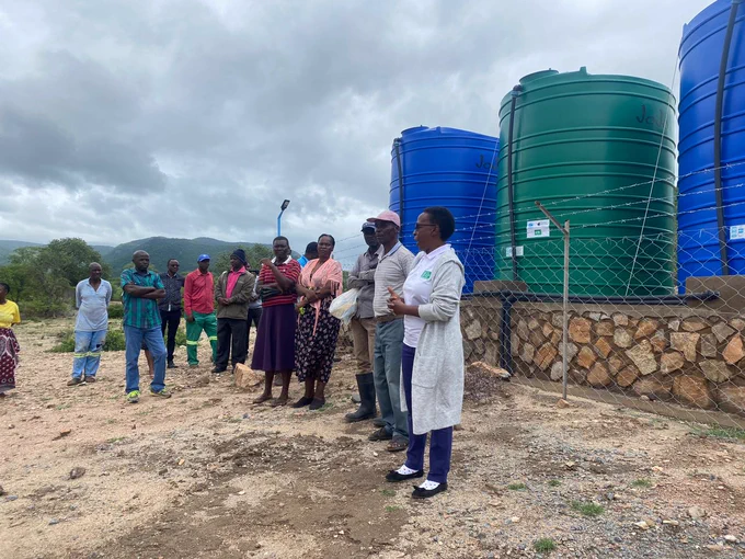 People stand in front of large plastic water tanks