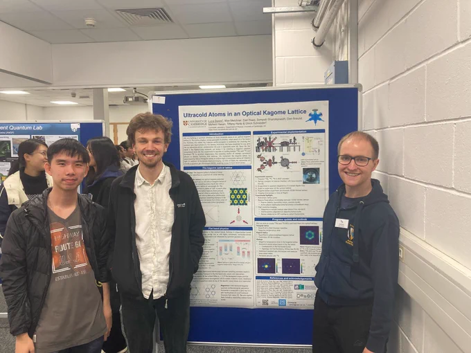 Three people stand smiling in front of a poster entitled 'Ultracold Atoms in an Optical Kagome Lattice'. They're in a small poster hall at the student conference, with some other people and their posters visible in the background.