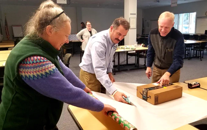 Three people wrapping a present.