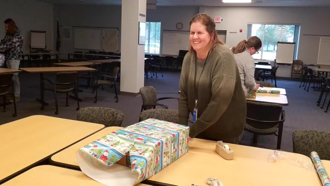 One person wrapping a present with people wrapping presents in the background.
