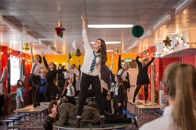 Still from Anna and the Apocalypse. A group of school pupils dance on tables, with Christmas decorations hanging from the walls.