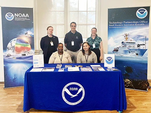 Five people behind a blue table surrounded by NOAA signage