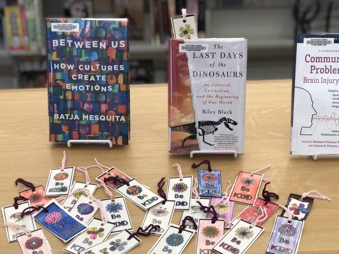 Laminated bookmarks that say "Be Kind" on display with library books