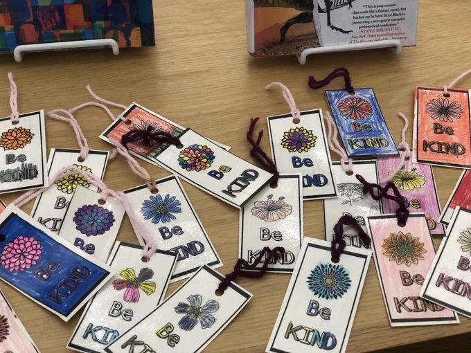 A closeup of laminated bookmarks that say "Be Kind" on display with library books