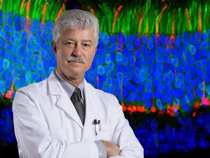 Steven J. Fliesler, PhD, stands against a backdrop of a research-related image