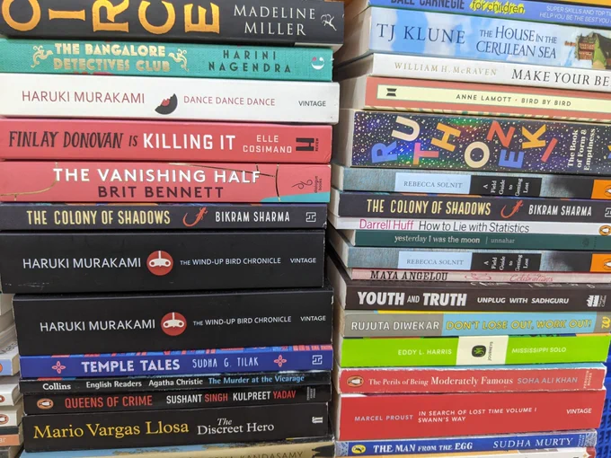 Photo of two stacks of books by different authors. Two copies of my book are sandwiched within the stacks. 