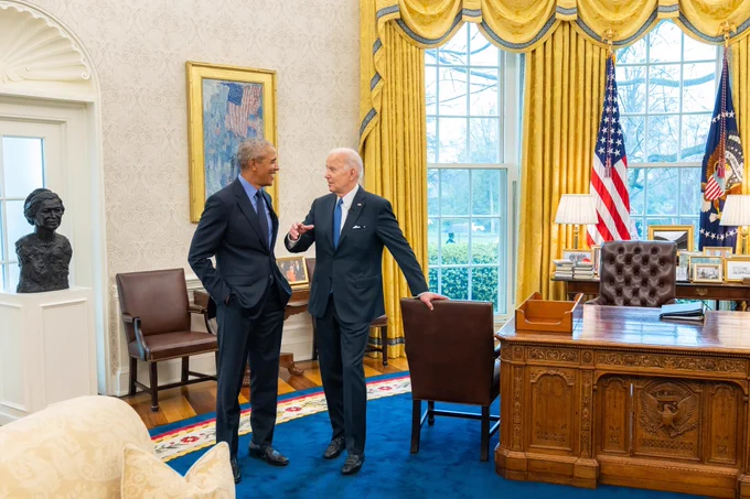 President Biden and President Obama stand in the Oval Office.