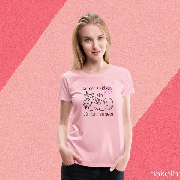 Foto eines Models, das ein T-Shirt in hellrosa trägt. Darauf ist ein Design von Purzel, dem tollpatschigen Einhorn abgedruckt. Dieses zeigt einen grinsenden Purzel mit einem Leuchtmarker im Maul. Darüber steht: "Keiner zu klein, ein Einhorn zu sein." Das Wort "klein" ist durchgestrichen und durch das Wort "dick" ersetzt.