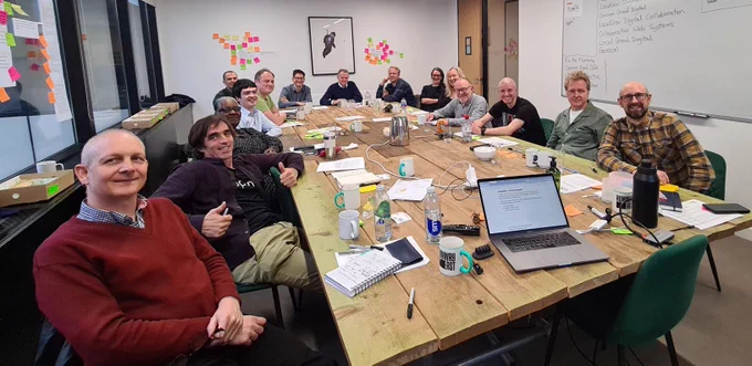 14 team members of LocalGov Drupal sitting round a large table.