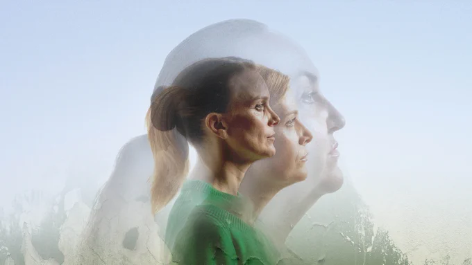Three faces of women looking solemnly to the right layered in transparency over one another. The first wears a bright green jumper. Background is a peeling, painted wall.