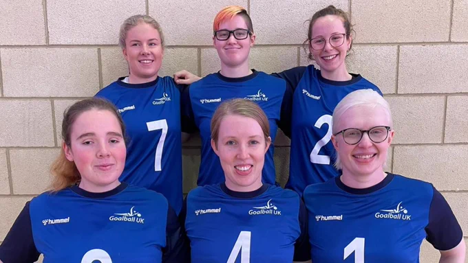 Group photo of the GB Women squad. Left to right top row is Megan, Amelia and Antonia. Bottom row is Lois, Georgie and Sarah. They are all wearing their blue hummel GB kit tops and smiling for the camera.