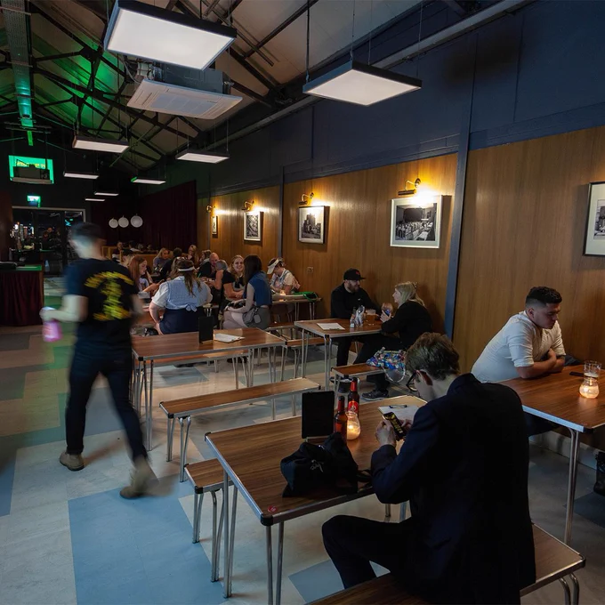 A busy dining area inside Neepsend Social Club. People are sitting in groups at the tables eating and drinking.
