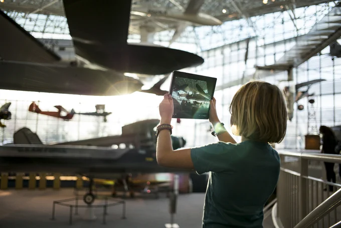 A student takes a photo in a museum with a tablet 