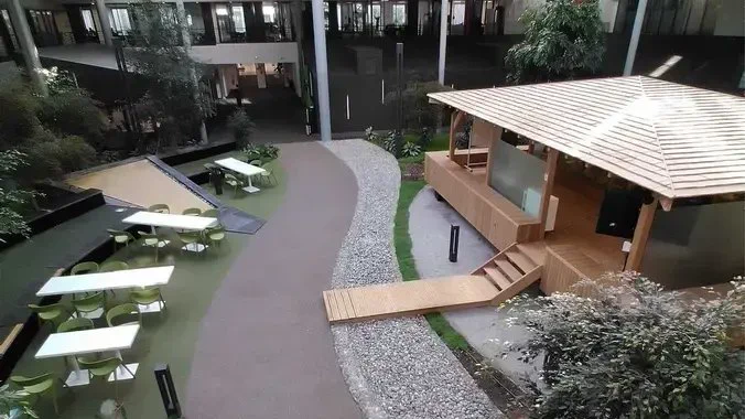 Photo prise en hauteur de l'espace zen intérieur au siège d'Adeo avec table et chaise, une fontaine et un espace de type bungalow