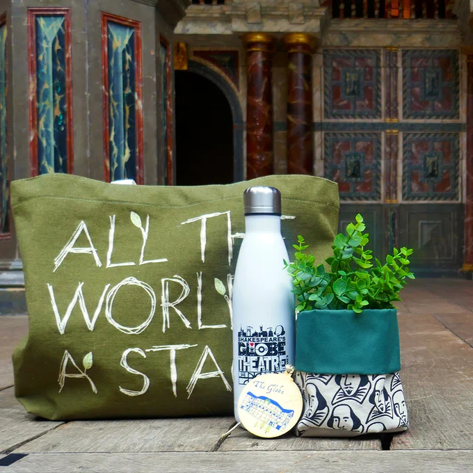 A green tote bag, reusable white water bottle, a wooden Christmas decoration and a green canvas plant pot sit on the Globe Theatre stage.