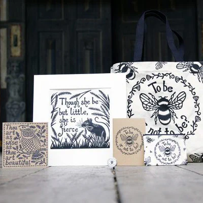 A greetings card and notebook made from kraft paper, and a lino print and tote bag with floral, nature and animal designs on the Globe Theatre stage.