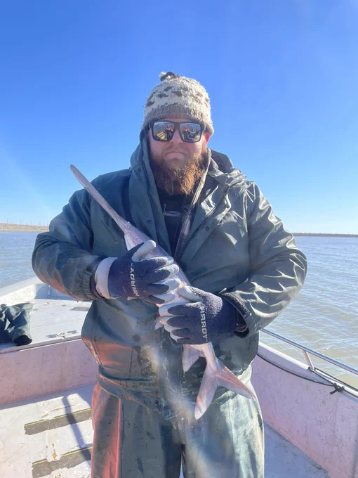 Mack is hugging a young paddlefish.