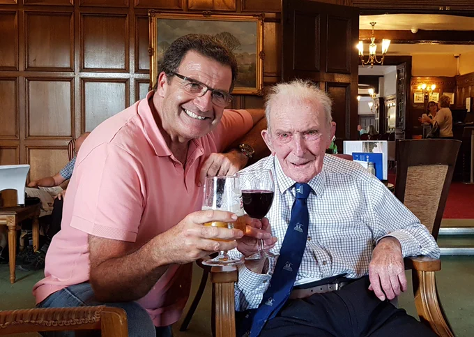 John and Johnny Johnson clinking glasses in the Petwood hotel wood-paneled bar