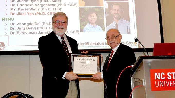 Richard Spontak accepts a plaque from Louis Martin-Vega, both of whom are smiling at the camera.