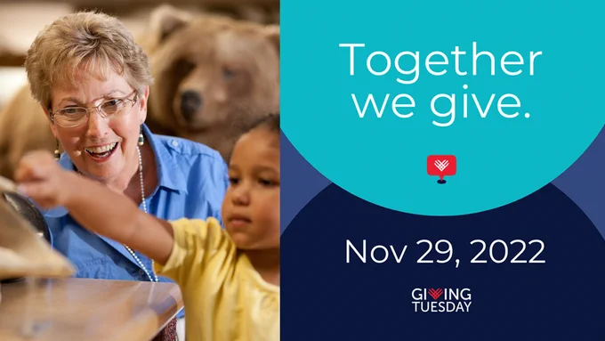 On the right side, a woman and child are looking at something together and there's a taxidermy bear in the background. On the right, white text on a blue background reads "Together we give. Nov 29, 2022