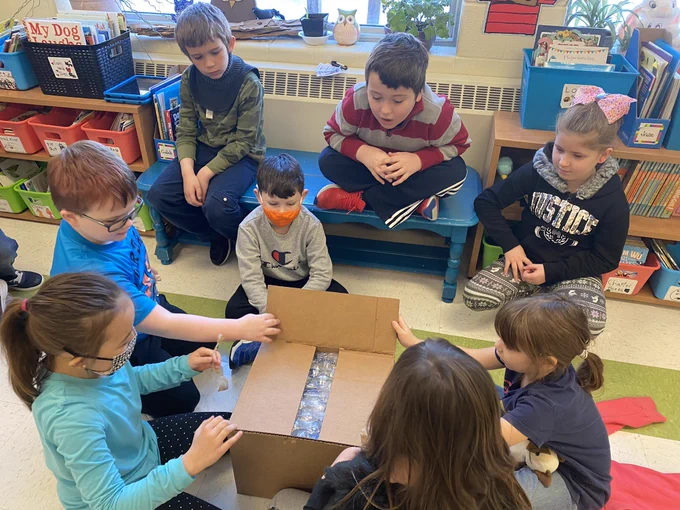 A group of school children open a delivery box full of books 