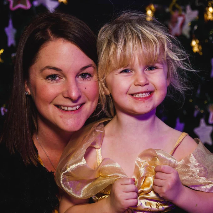Woman and young girl smiling at the camera.