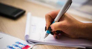 This is a photo of a woman writing notes down in her notebook.