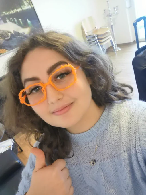 Zu sehen ist eine Mitarbeiterin von PIKSL. Sie hat die selbstgedruckte Brille an. Die Brille ist Orange.
