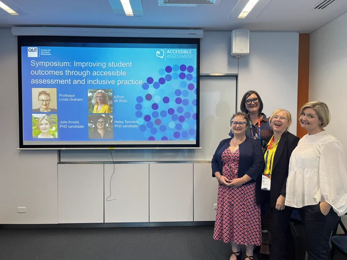 Image: top left side of photo show the front slide of the presentation with title: Improving student outcomes through accessible assessment and inclusive practice. On the right four women stand, from left to right: Prof Linda Graham, Haley Tancredi, A/Prof Jill Willis and Julie Arnold.