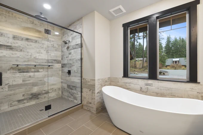 Walk in shower with wood grain tile and glass door built by Lexar Homes of Suncadia