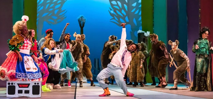 A cast of characters on a brightly decorated stage are in a dance battle with a group of rats.
