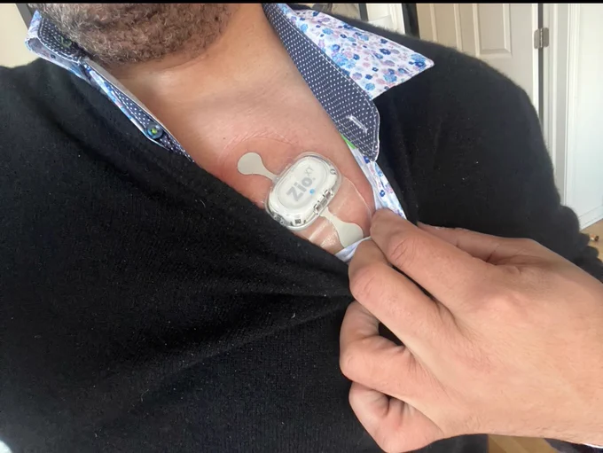 Steven Thrahser pulling down his shirt and revealing a Zia patch on his chest 