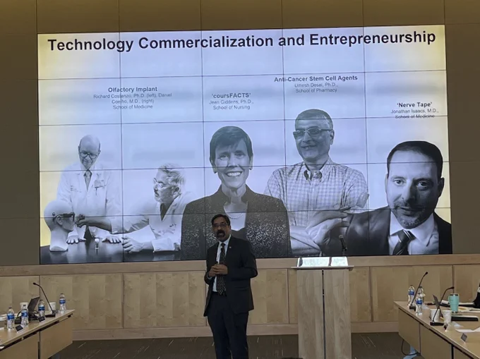 Sriram Rao presenting the State of the Research presentation to VCU's Board of Visitors. The slide he is presenting has the title, "Technology commercialization and entrepreneurship" and features VCU researchers. 