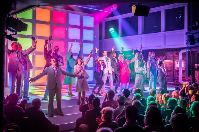 Tammy Faye cast bathed by rainbow lights at the curtain call