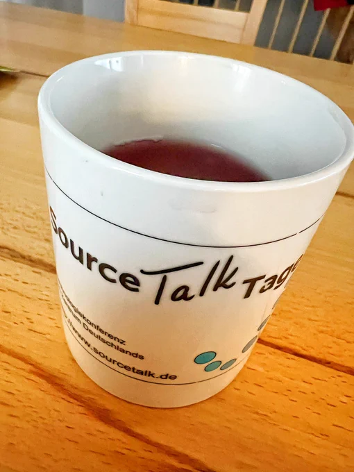 Mug on a table with tea in it. Logo of the German "source talk tage" on it.