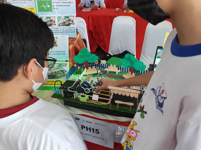 Smart traffic control project with a microbit controlling a traffic intersection, a lego man has now crossed and the vehicle is being pushed through in the young person's hand. 